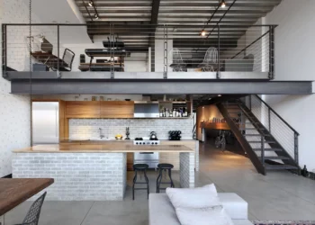 A furnished loft with stair bed chairs table and sofa -