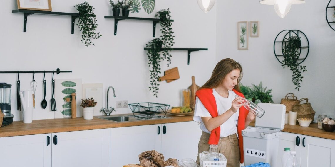 A women in the kitchen holding a glass bottle Depicting greener home