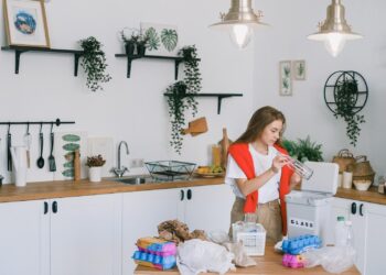 A women in the kitchen holding a glass bottle Depicting greener home
