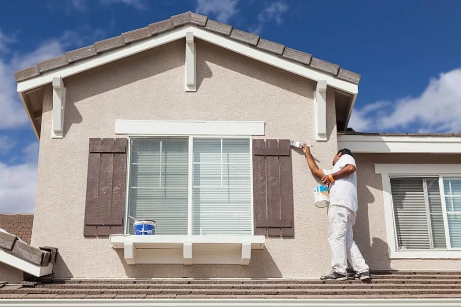 A man painting the exterior of a home