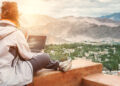 A women sitting on the cliff using her laptop looking for realtors