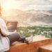 A women sitting on the cliff using her laptop looking for realtors