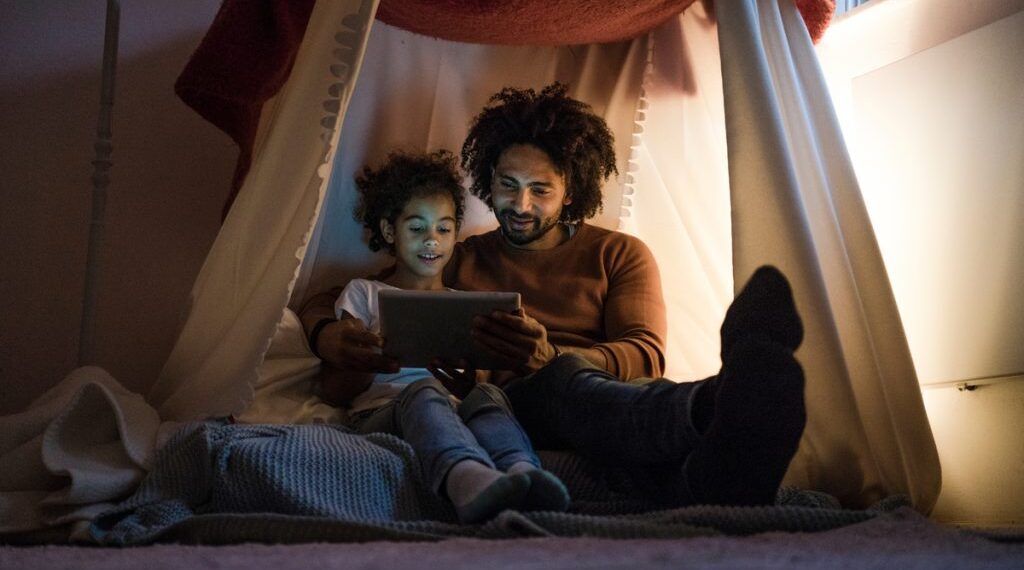 A father with his son sitting in the dim light to save energy