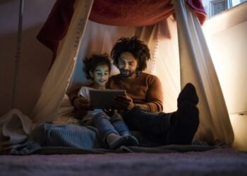 A father with his son sitting in the dim light to save energy
