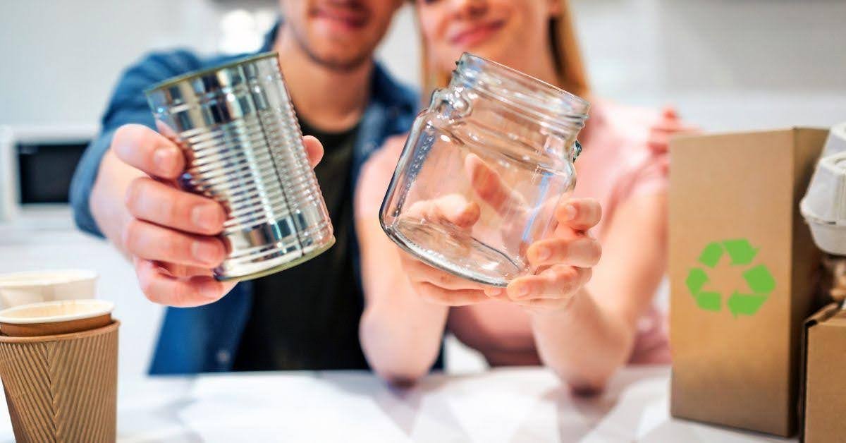 A couple holding metal and glass jars indicating eco-friendly upcycling.
