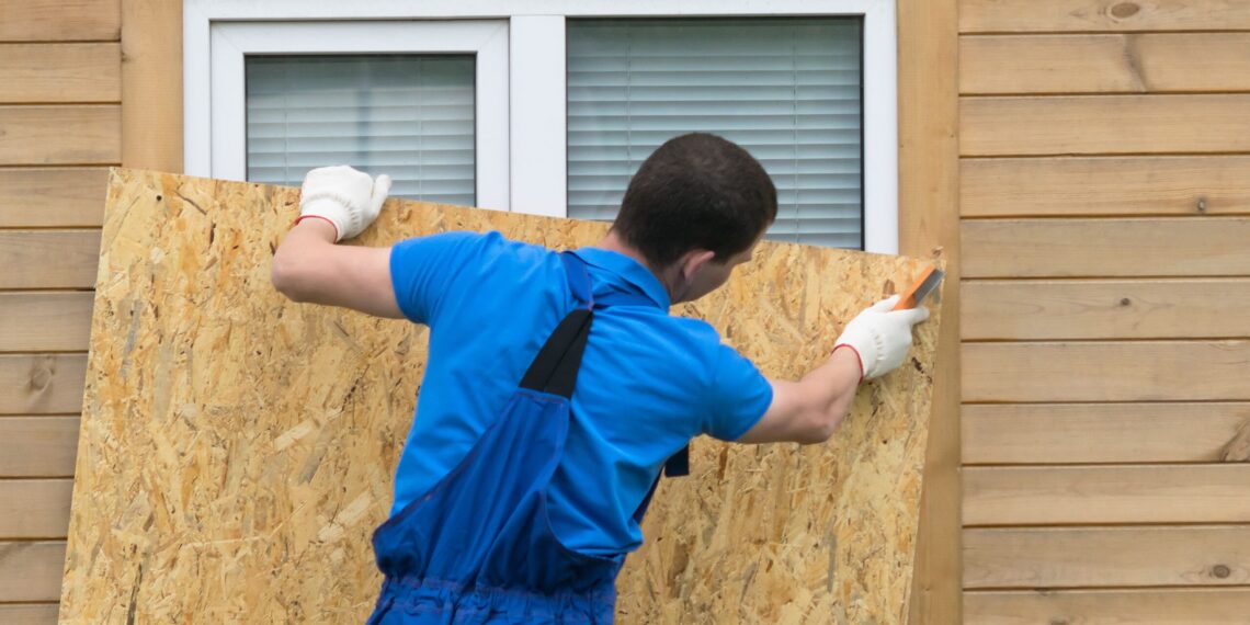 A Person boarding up the window for protecting his home from hurricane
