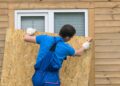 A Person boarding up the window for protecting his home from hurricane