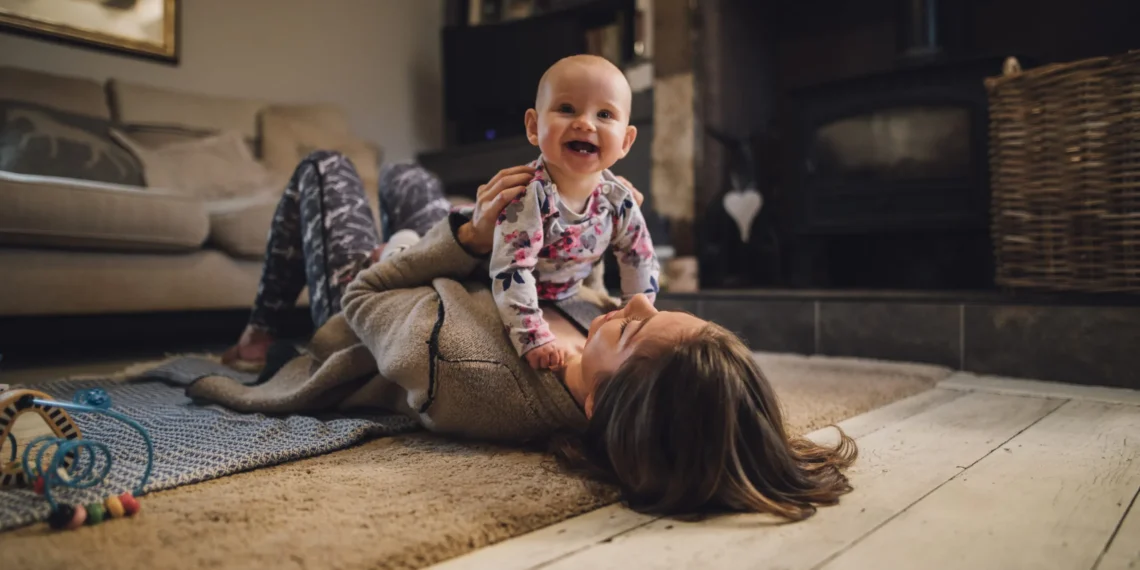 A women laying down with an infant sitting on her stomach
