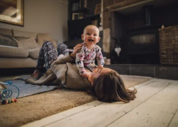 A women laying down with an infant sitting on her stomach