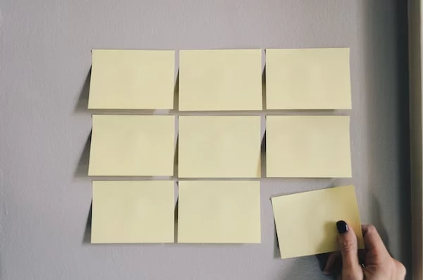 A hand removing a sticky note from the wall